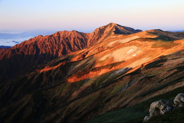Fototapeta premium 東北飯豊連峰 飯豊山山頂直下本山小屋の朝 朝陽に映える大日岳の雄姿と稜線