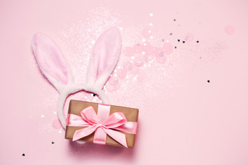 Top view and flat lay of Easter symbol - bunny ears and gift box on pink background. Festive and bright, confetti and sparks. Easter greetings