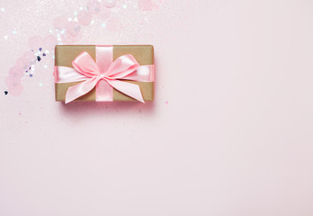 Gift box and Pink confetti and stars and sparkles on pink background. Top view, flat lay. Bright and festive holiday background. For Christmas, New year, Mother's day, International woman's day