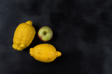 Two trendy organic lemons and one Apple on a dark background. Horizontal orientation.