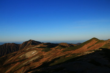 東北飯豊連峰　飯豊山山頂直下本山小屋の朝　朝陽に映える飯豊本山と大日岳の雄姿と稜線