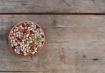 Mixture of beans varieties,azuki and green lentils in a bowl on a weathered wooden plank. Food background for copy space