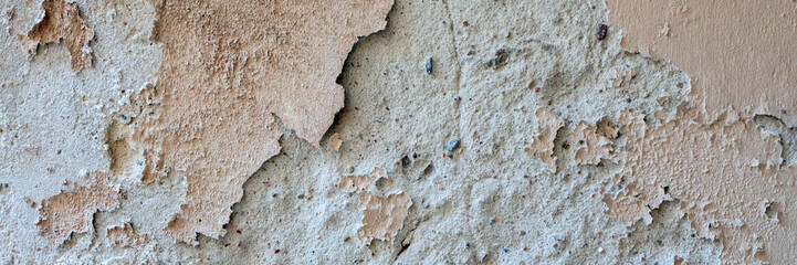 Old grungy weathered wall background texture. Beige dirty peeled plaster wall with falling off flakes of paint
