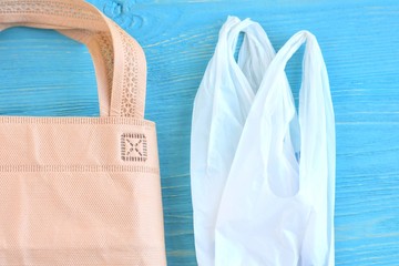 Plastic bag and cotton bag with selective focus on blue background. Zero waste concept. Reduce plastic bags use to protect the environment. Textile and polyethylene bags for packaging groceries 