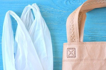 Plastic bag and cotton bag with selective focus on blue background. Zero waste concept. Reduce...