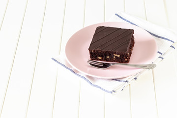 Homemade dark chocolate vegan brownie cake with nuts plate light background. Selective focus.