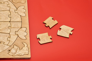 wooden puzzle in the form of the alphabet on red background
