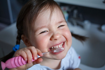  the child is learning to brush their teeth. Hygiene and health of children's teeth. Little girl...