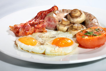 Traditional English breakfast of fried eggs, bacon, fried mushrooms and tomato,