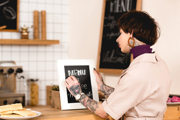 Fototapeta na wymiar pretty businesswoman writing on menu board while standing at bar counter