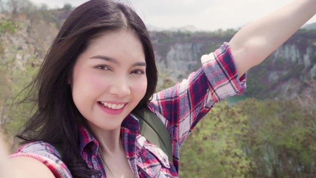 Asian backpacker woman selfie on top of mountain, young female happy using mobile phone taking selfie enjoy holidays on hiking adventure. Lifestyle women travel and relax concept.