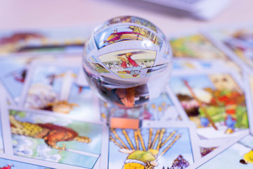 The crystal ball of predictions stands on the background of tarot cards. Blurred card background