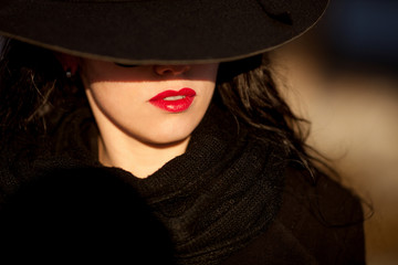 Young woman posing in black coat and black hat.