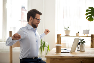 Satisfied businessman sitting at the desk relaxing in office