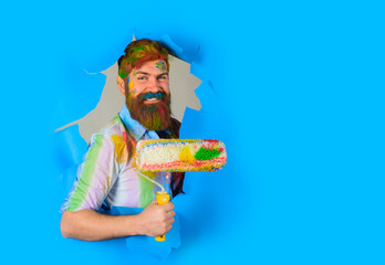 Painter. Through paper. Repair tools. Bearded painter with paint roller. Room painting. Hard hat. Construction. Industrial concept. Repair. Bearded man through paper.