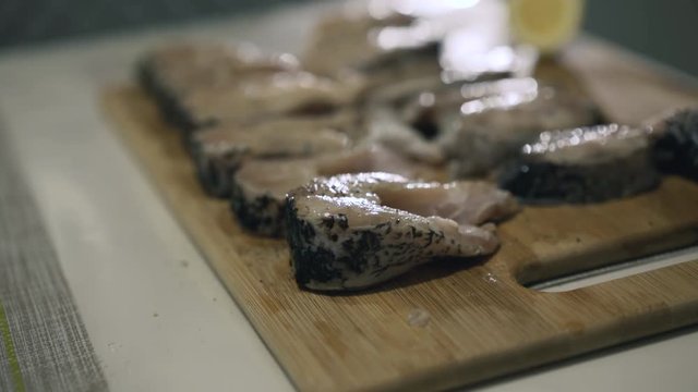 Female hands marinate fish fillet on wooden tablet. 4K