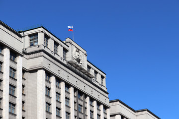 Russian flag on the Parliament building in Moscow against blue sky. Facade of State Duma of Russia...