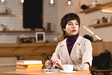 Fototapeta premium attractive, serious businesswoman sitting at table in cafeteria