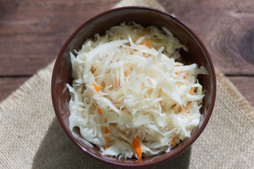 sauerkraut with carrots in a bowl on a wooden background