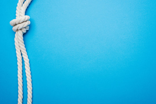 white long ropes with sea knot isolated on blue