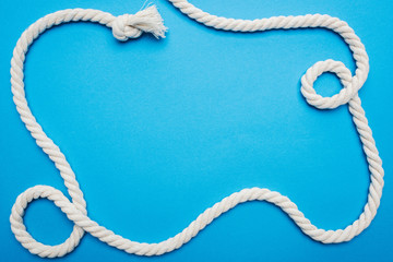 top view of white waved long rope with knot isolated on blue