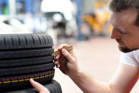 Mechaniker mi&szlig;t Profiltiefe eines Autoreifens in der Autowerkstatt // Mechanic measures tread depth of a car tyre in the car repair shop