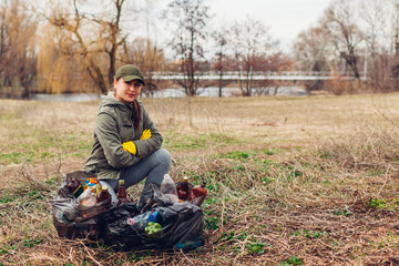 Woman volunteer cleaned up the trash in park. People picked up garbage and showing result with full...