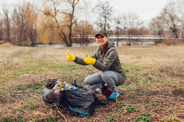Woman volunteer cleaned up the trash in park. People picked up garbage and showing result with full...