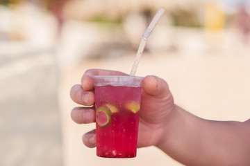 Men's hand with delicious cocktail on a sunny summer beach - Image