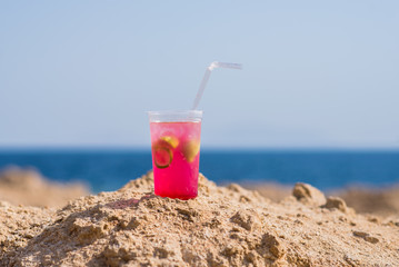 Bright cocktail placed on a sunny summer beach against the blue sea - Image