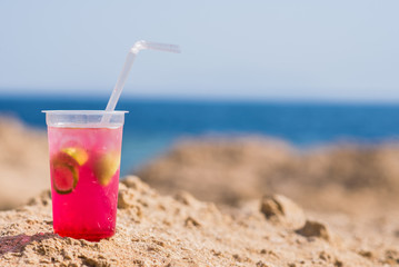 Bright cocktail placed on a sunny summer beach against the blue sea - Image