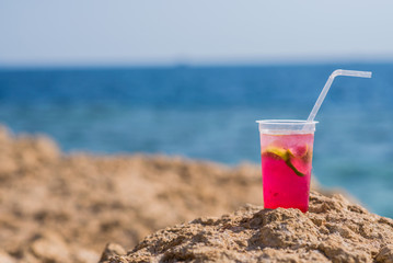Bright cocktail placed on a sunny summer beach against the blue sea - Image