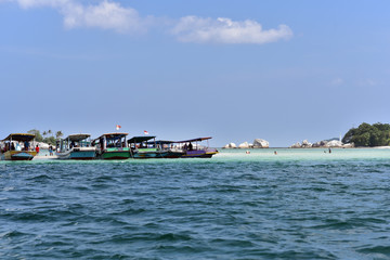 Touristic boats and swimming people near Lengkuas Island, Belitung Island, Indonesia
