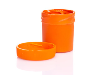 Opened orange Gouache jar, isolated on white background with copy space. Cans of different colors gouache paints.