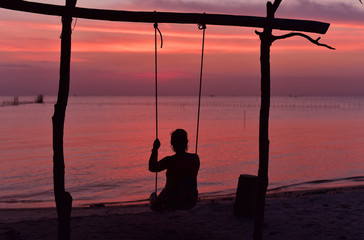 Silhouette of an Indonesian girl having some on a swing at Penyabong Beach in Belitung Island, Indonesia