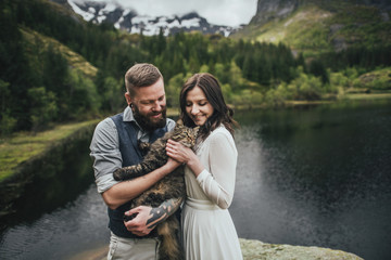 Wedding couple travelers on a hill in Norway, Kvalvika. Beautiful view of the beach, Lofoten, Norway.