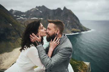 Wedding couple travelers on a hill in Norway, Kvalvika. Beautiful view of the beach, Lofoten, Norway.