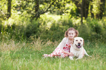 Cute smiling little girl hugging and  ironing labrador in the summer park
