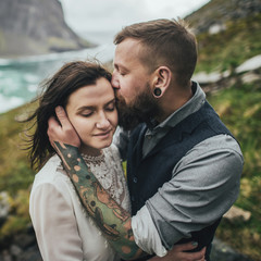 Wedding couple travelers on a hill in Norway, Kvalvika. Beautiful view of the beach, Lofoten, Norway.