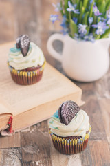 Handmade chocolate muffins with decorations. Book and a bouquet of Scilla, blurred background