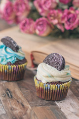 Handmade chocolate muffins with decorations. Book and a bouquet of roses, blurred background