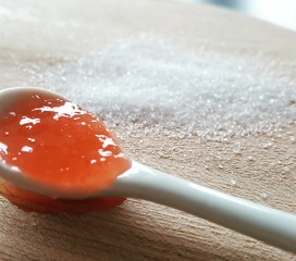 Peach marmelade with sugar on wood in background