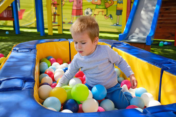 Little boy playing with colorful balls in park playground