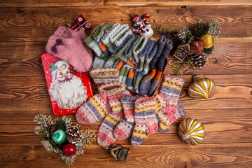 multi-colored knitted baby socks, Christmas decorations and a metal box with the image of Santa Claus on a wooden background