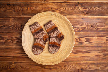 multi-colored knitted baby socks in a wooden plate on a wooden background