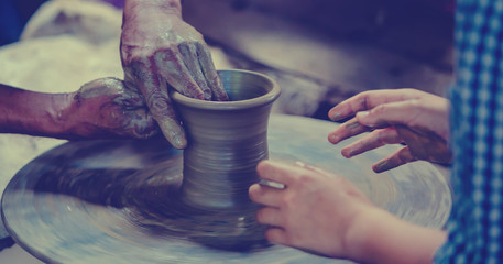 Making it together. close-up to hands of potter teacher and child