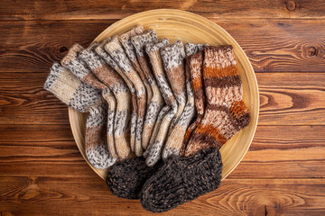 multi-colored knitted baby socks in a wooden plate on a wooden background
