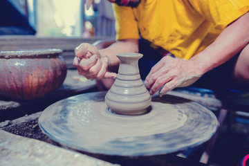 pottery, workshop, ceramics art concept - closeup on male hands sculpt new utensil with a tools and water