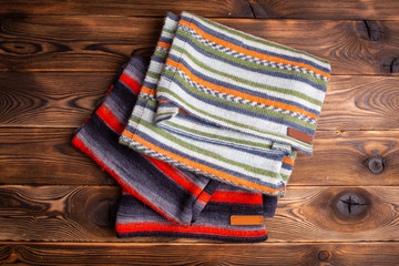 knitted striped scarves on wooden background