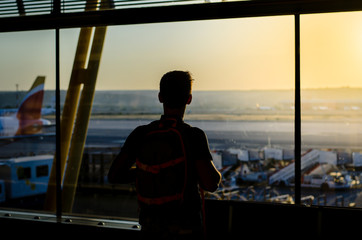 Thoughtful young man looking by the window at a airport terminal
